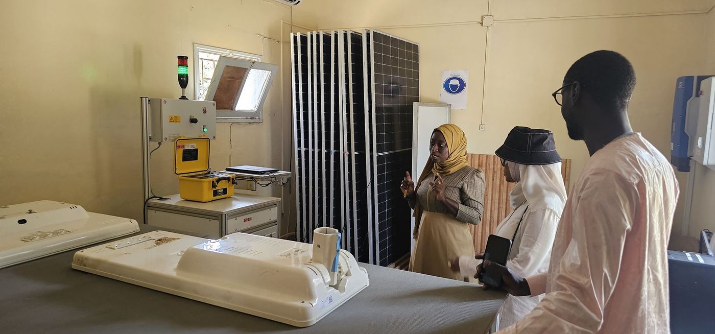 Visite d’un laboratoire d’essais, devant des panneaux solaires et un banc de mesure