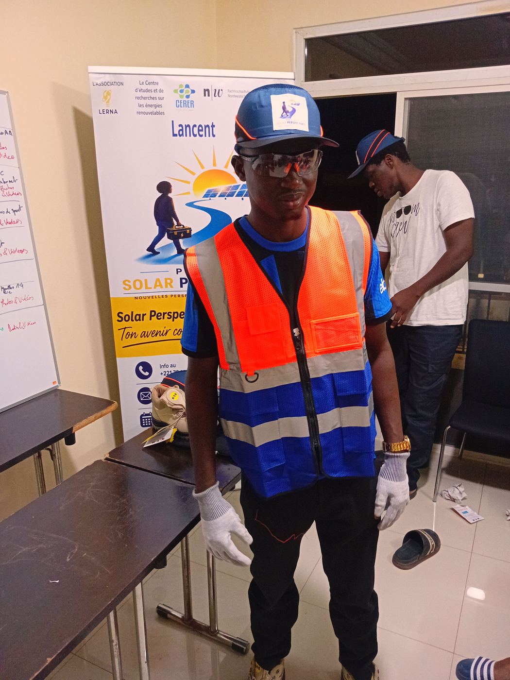 Un apprenant en tenue de chantier, gilet et casquette du projet