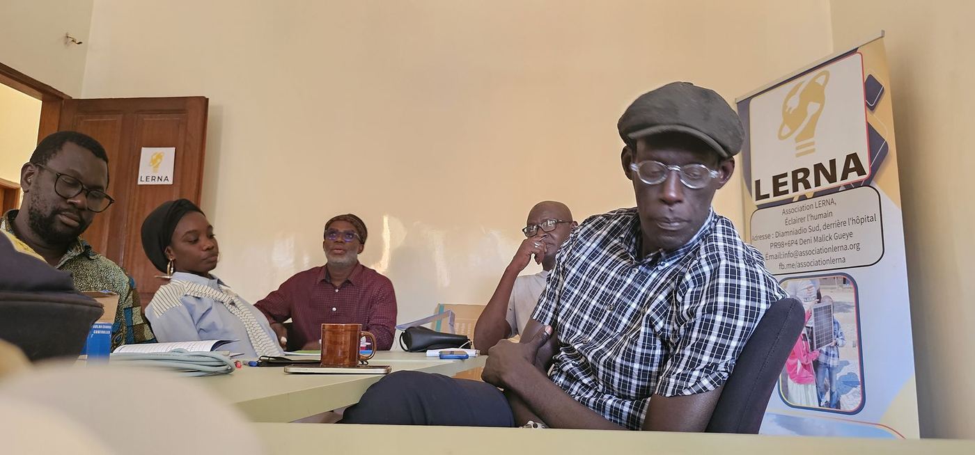 Les participants échangent autour d’une table, devant la bannière de LERNA