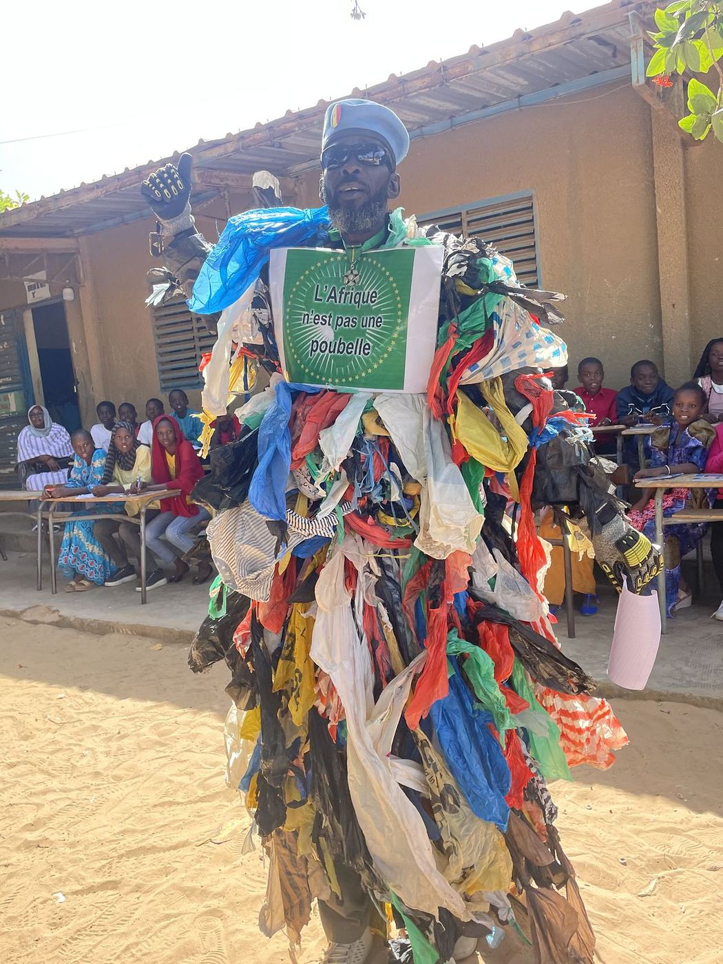 Un personnage costumé de sacs plastique, dans la cour de l’école