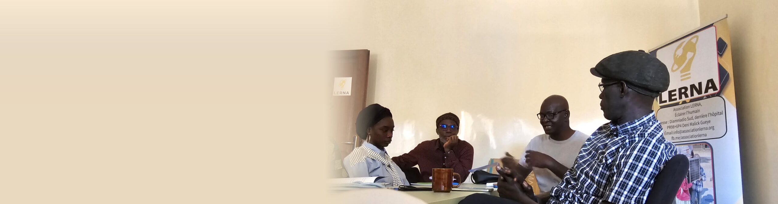 Échange autour de la table du bureau de LERNA, à Diamniadio, devant la bannière de l’association