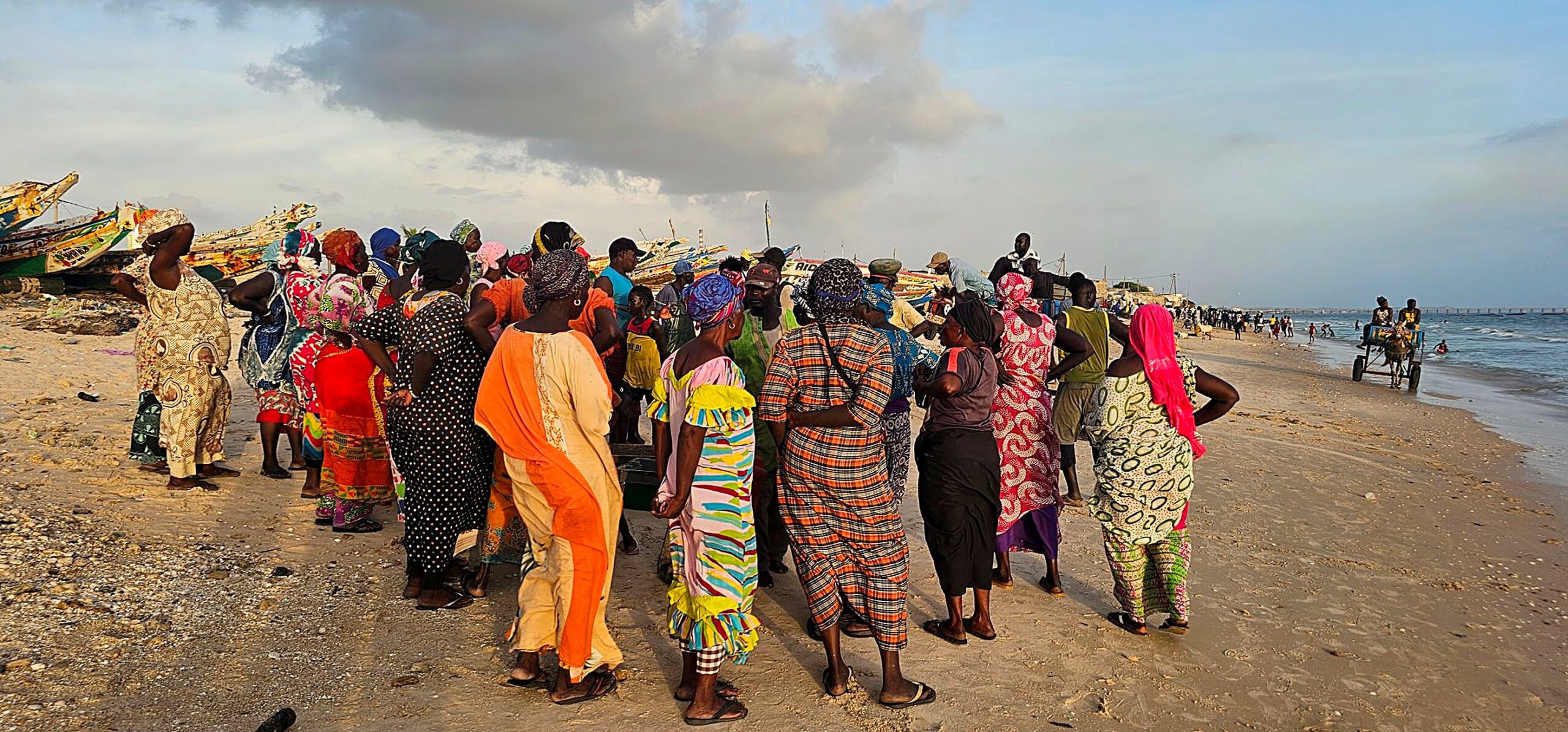 Des femmes rassemblées sur une plage de pêcheurs, au Sénégal, devant les pirogues