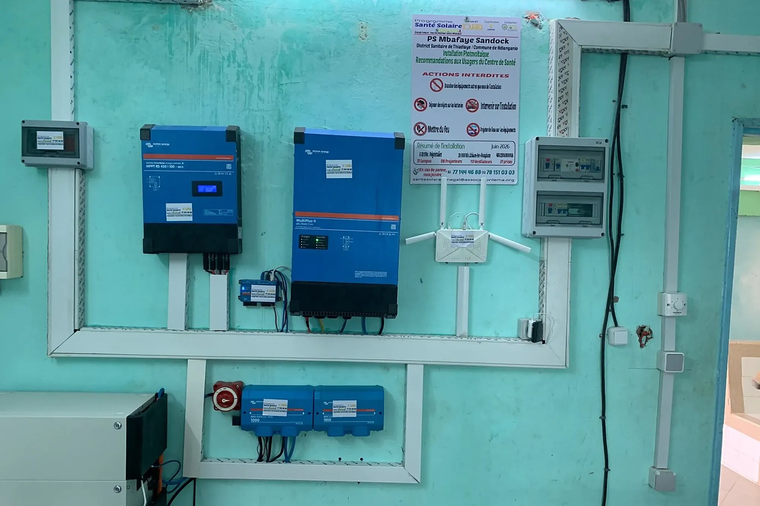 L’installation solaire d’un poste de santé, posée au mur : régulateur, onduleur, tableaux électriques et affiche de recommandations