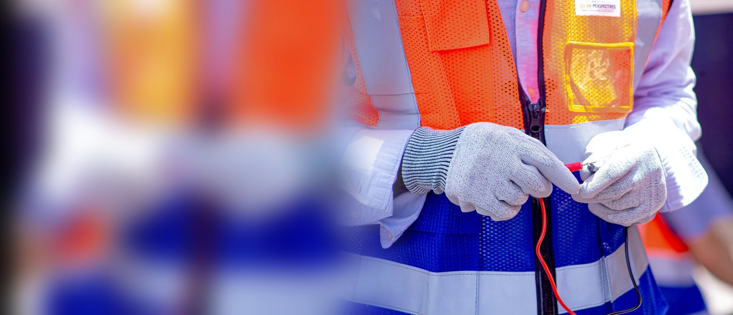 Mains gantées d’un stagiaire de Solar Perspectives tenant les pointes de mesure d’un multimètre