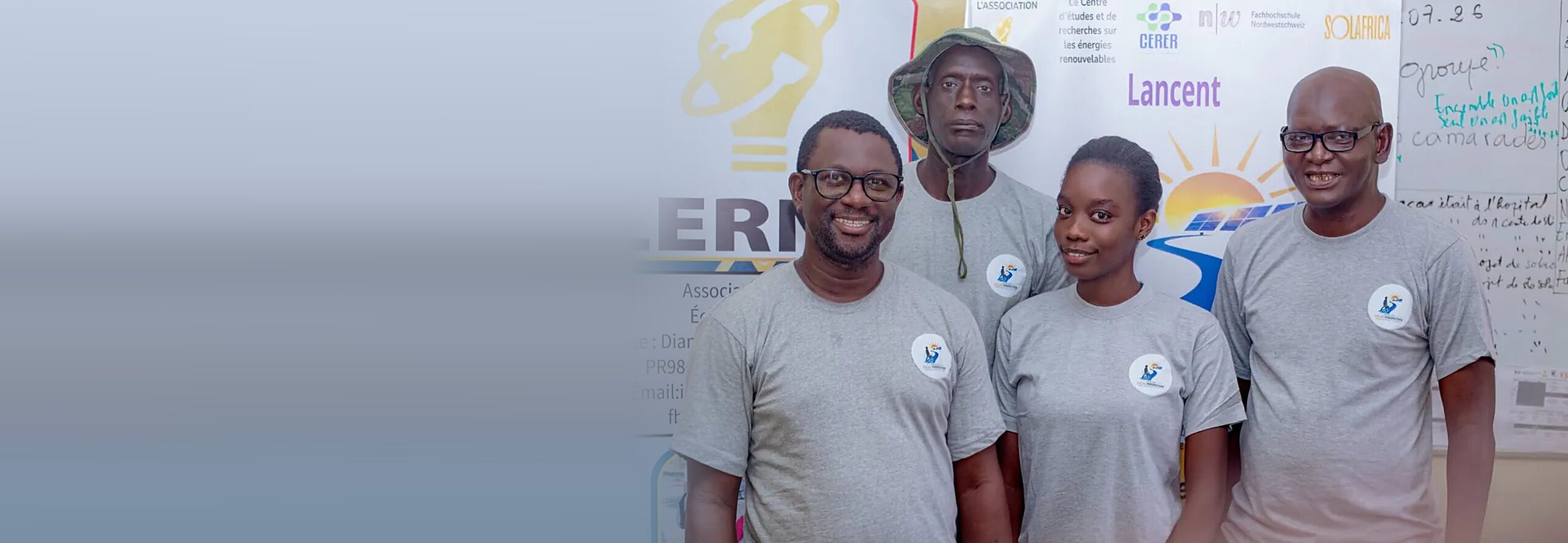 Quatre membres de LERNA en t-shirt Solar Perspectives, souriants, devant les affiches de l’association
