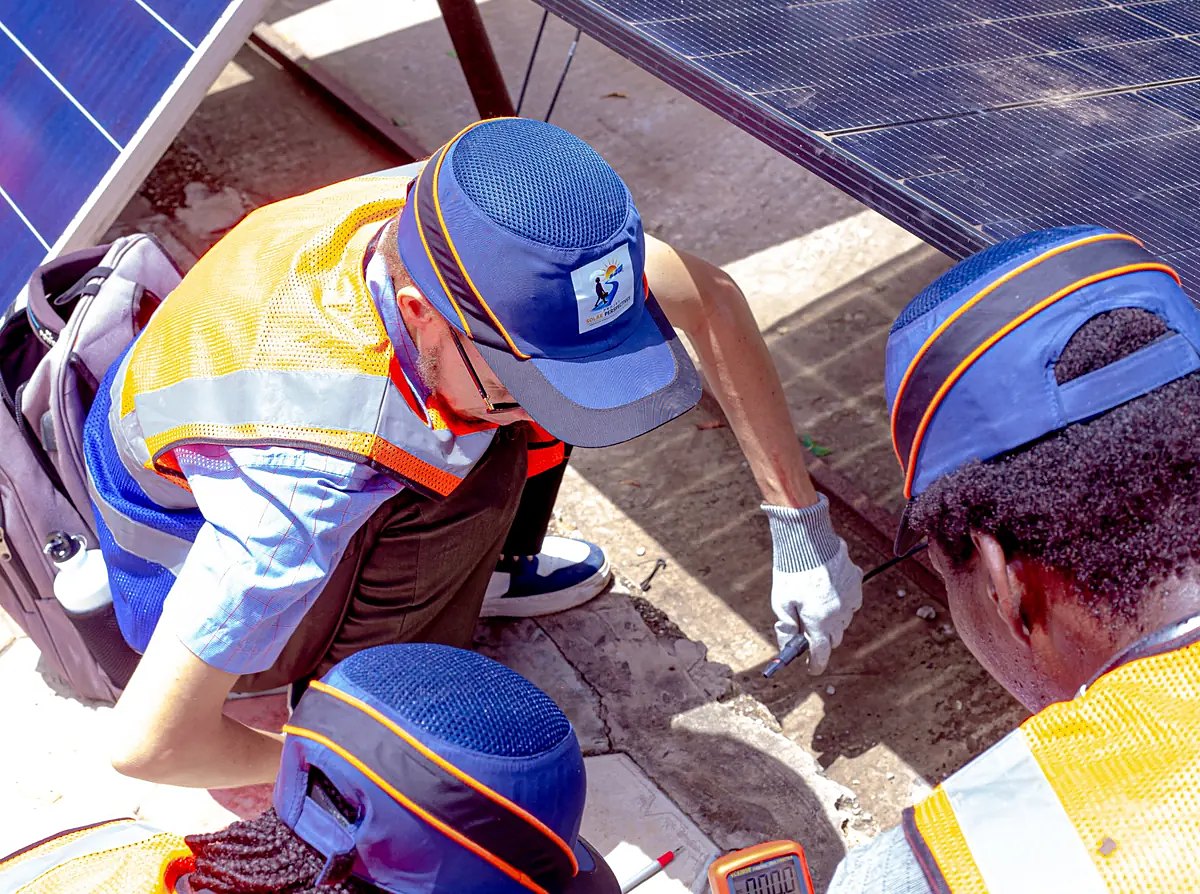 Un formateur montre une mesure aux stagiaires, sous des panneaux solaires