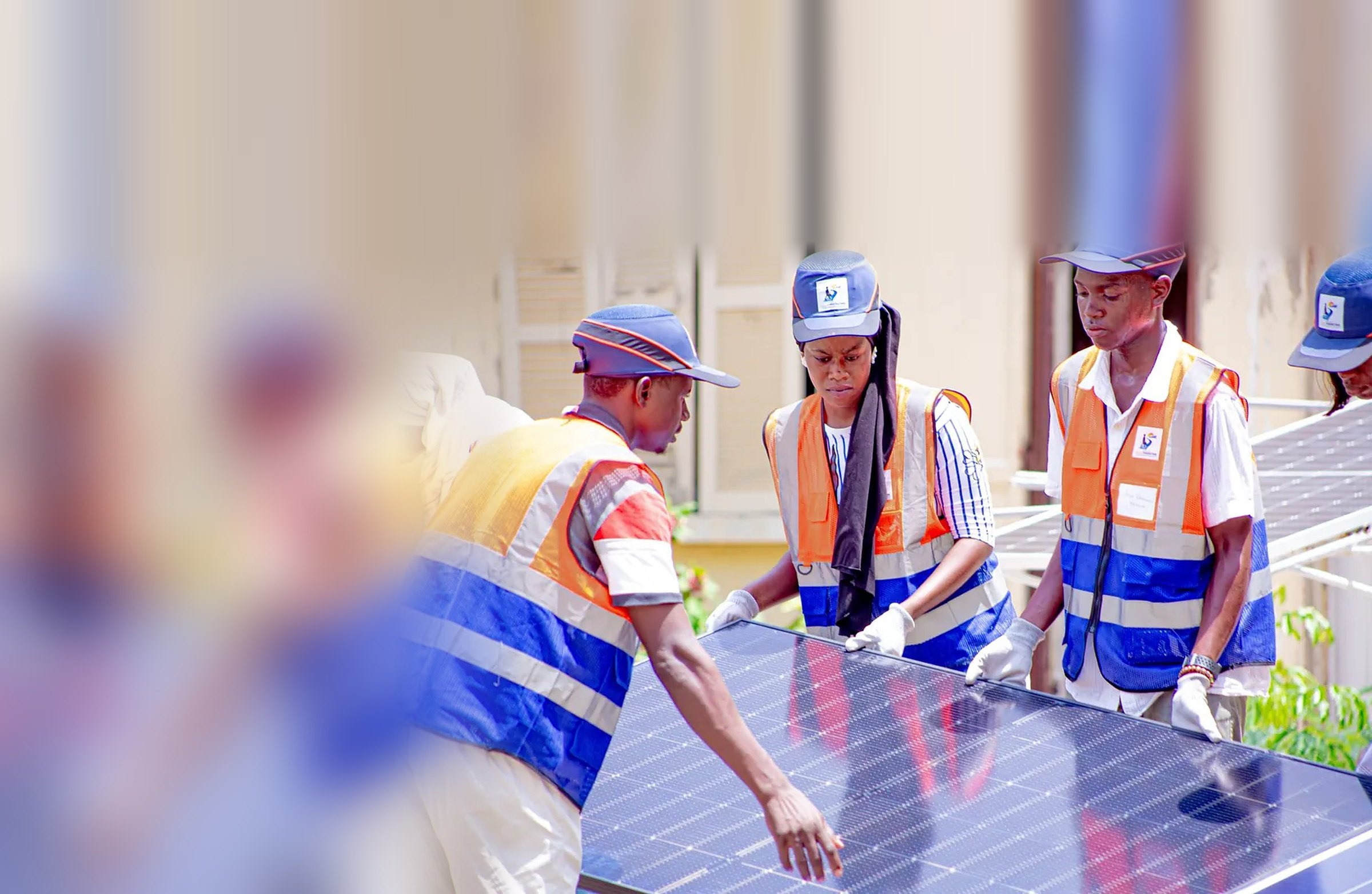 Trois stagiaires de Solar Perspectives, en gilet et casquette, manipulent un panneau solaire