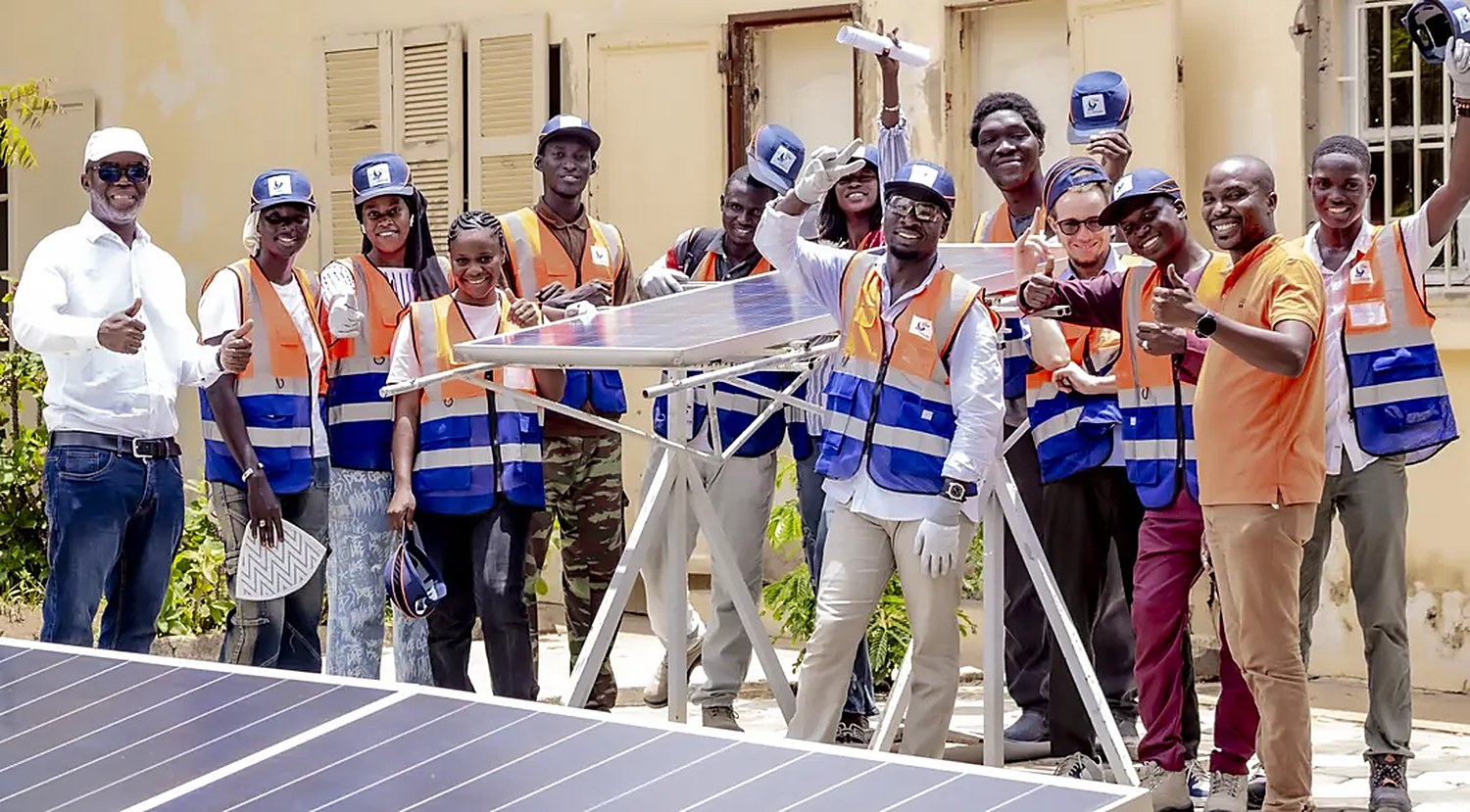 Les stagiaires de Solar Perspectives, en gilet et casquette, pouce levé autour d’un panneau solaire