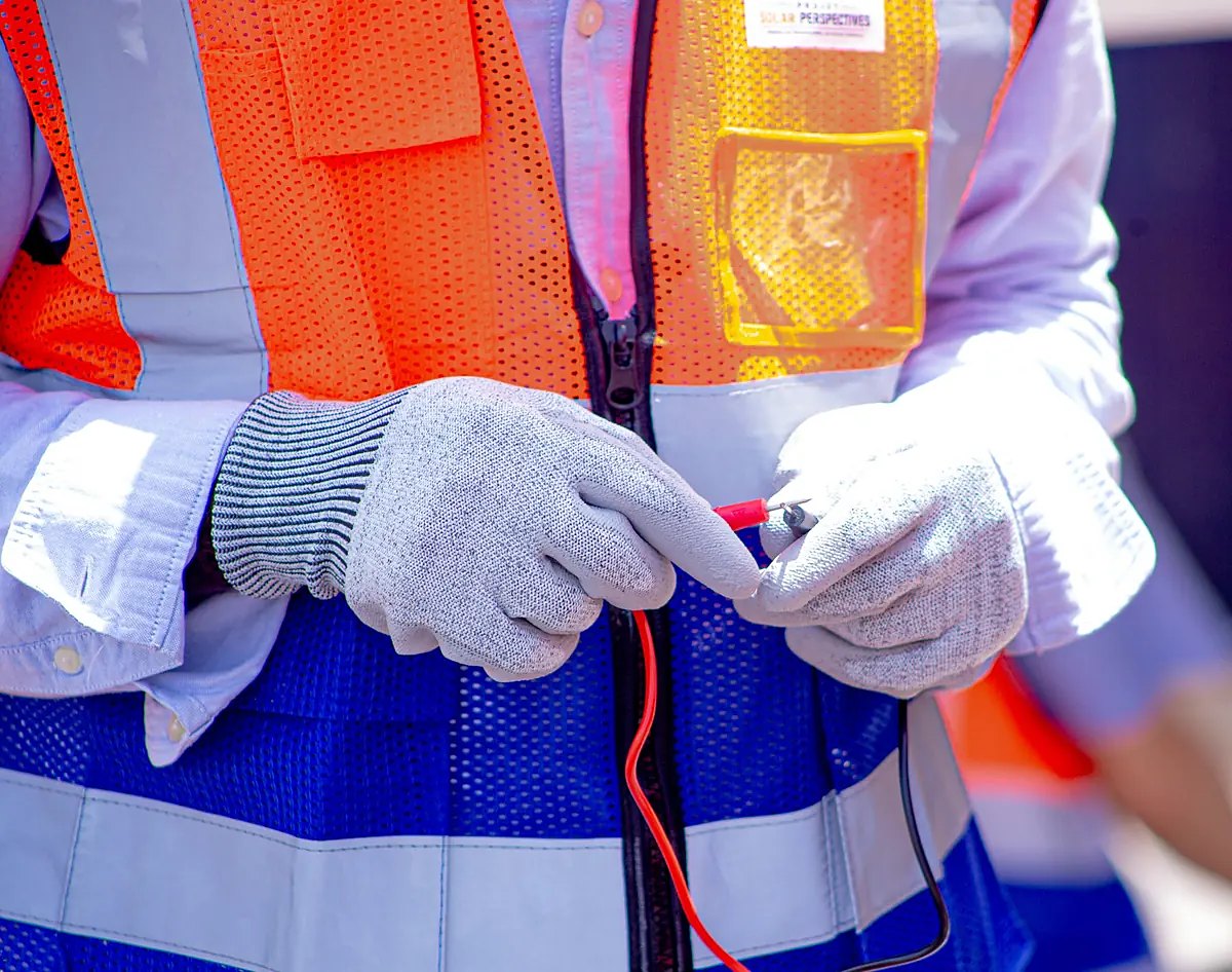 Mains gantées tenant les pointes de mesure d’un multimètre