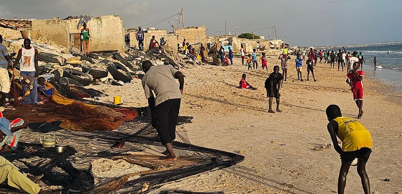 Des pêcheurs étendent leurs filets sur une plage animée, au bord de l’océan