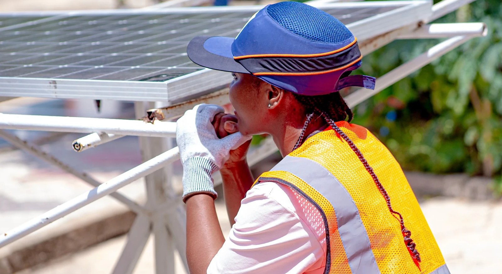 Une stagiaire observe la fixation d’un panneau solaire sur sa structure